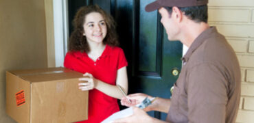 Delivery man brings a package to a customer's door and waits for a signature.